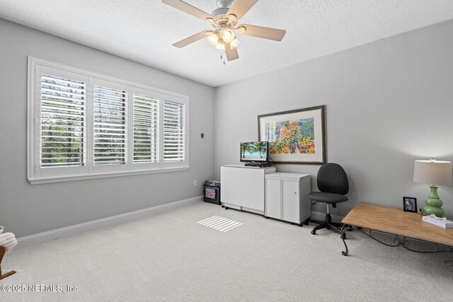 office area featuring a textured ceiling, a ceiling fan, baseboards, and carpet floors