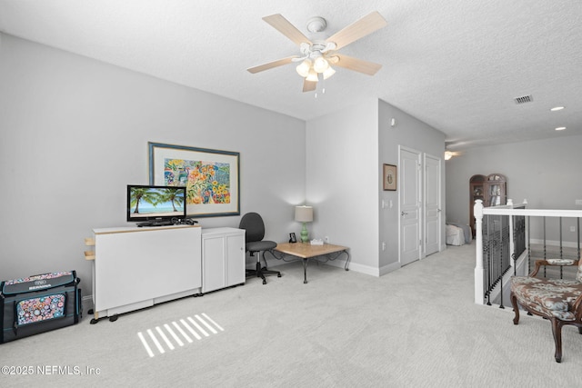 carpeted office with ceiling fan, baseboards, visible vents, and a textured ceiling