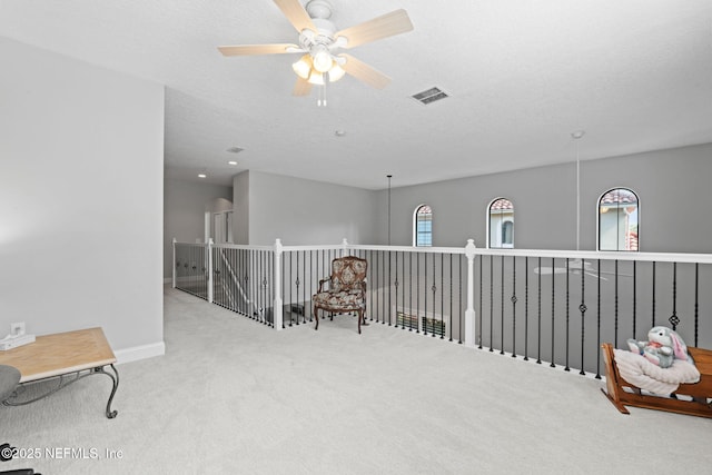 sitting room featuring visible vents, a textured ceiling, carpet, and a ceiling fan