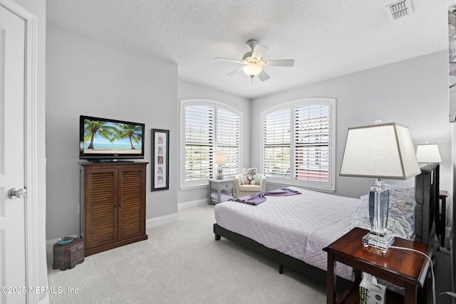 carpeted bedroom featuring visible vents, baseboards, a textured ceiling, and a ceiling fan