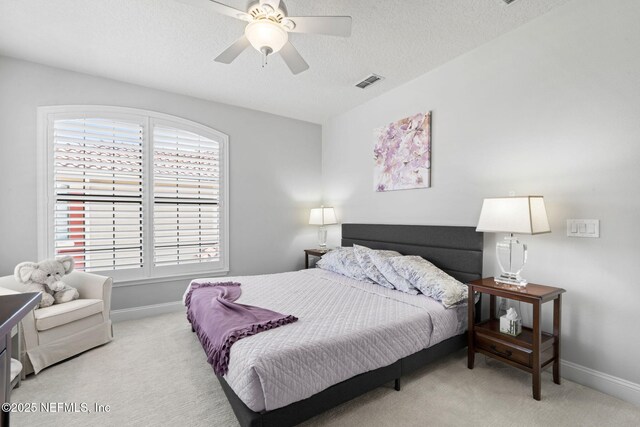 bedroom featuring light carpet, visible vents, a textured ceiling, and baseboards