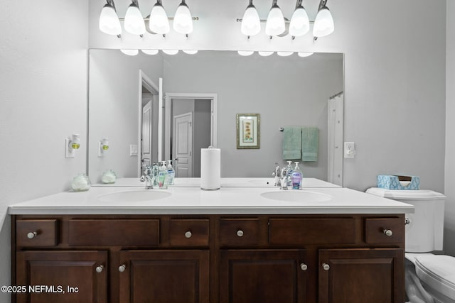 bathroom with double vanity, toilet, and a sink