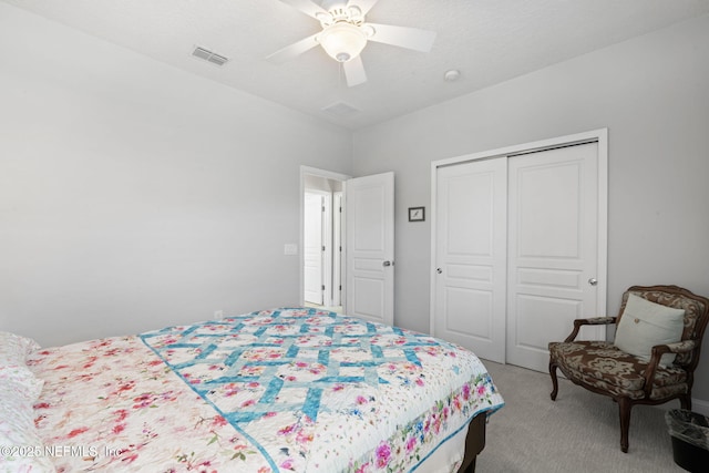 bedroom featuring visible vents, light colored carpet, a closet, and ceiling fan