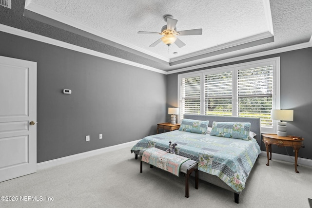 carpeted bedroom featuring a raised ceiling, a ceiling fan, a textured ceiling, crown molding, and baseboards