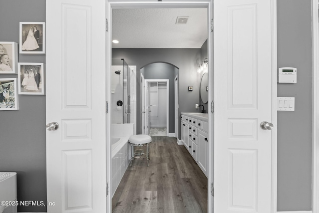 bathroom with visible vents, wood finished floors, a shower, a bath, and vanity