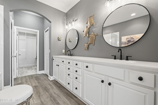 bathroom featuring double vanity, wood finished floors, baseboards, and a sink