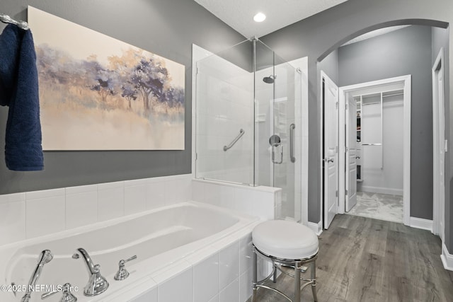 bathroom with a garden tub, wood finished floors, a stall shower, and baseboards