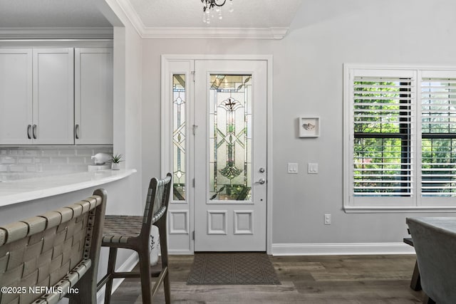 foyer featuring baseboards, a textured ceiling, dark wood-style floors, and ornamental molding