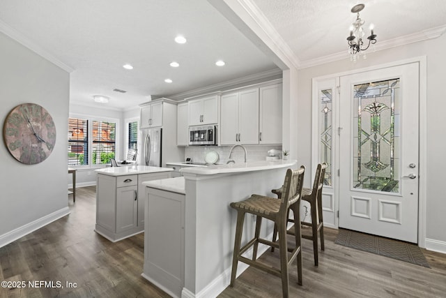 kitchen featuring appliances with stainless steel finishes, ornamental molding, a center island, and light countertops