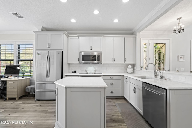 kitchen featuring visible vents, a sink, light countertops, appliances with stainless steel finishes, and crown molding