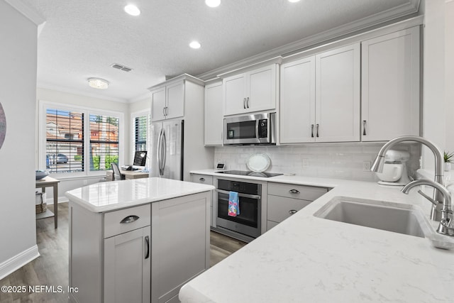 kitchen with visible vents, a sink, a center island, appliances with stainless steel finishes, and crown molding