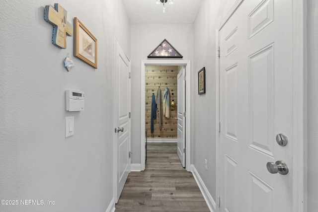 hall featuring baseboards, dark wood-type flooring, and a textured ceiling