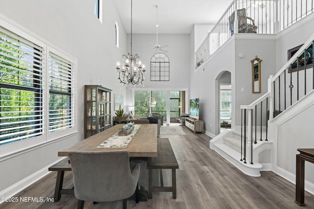 dining space with stairway, baseboards, dark wood-style flooring, and arched walkways