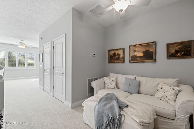 carpeted living room with visible vents, baseboards, a textured ceiling, and ceiling fan