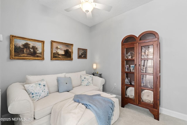 carpeted living area featuring a ceiling fan, baseboards, and a textured ceiling