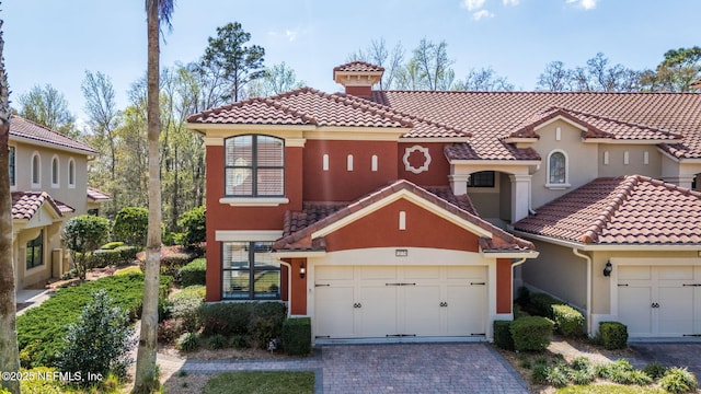 mediterranean / spanish house featuring stucco siding, a tile roof, and decorative driveway