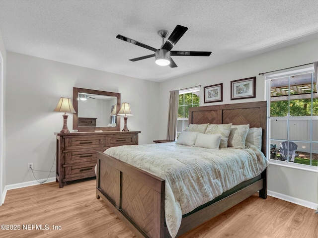 bedroom featuring a ceiling fan, baseboards, a textured ceiling, and light wood finished floors