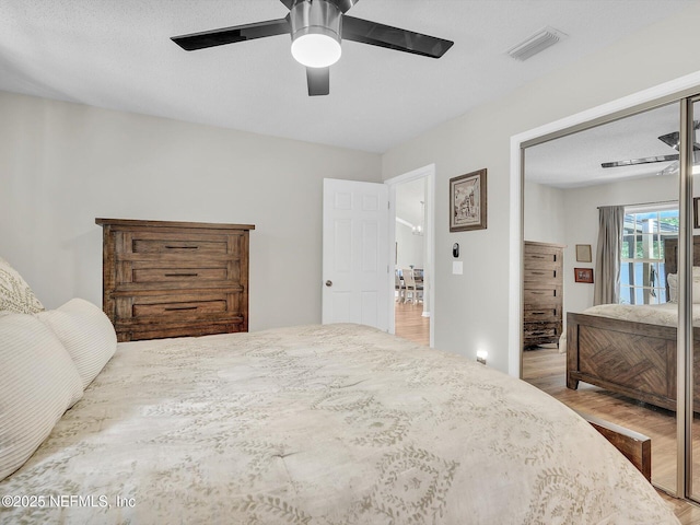 bedroom with access to outside, visible vents, ceiling fan, and wood finished floors