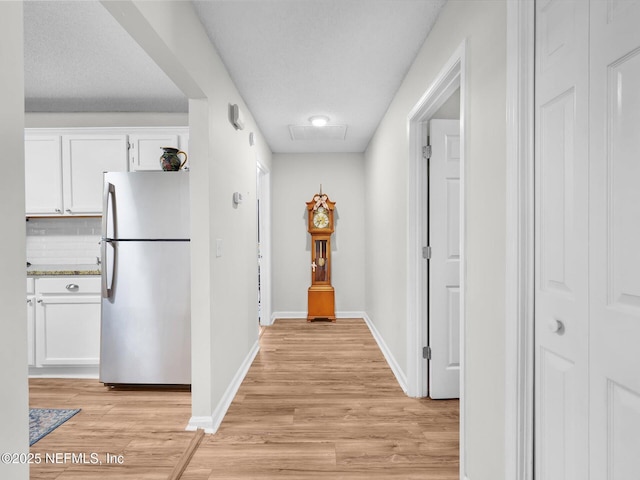 corridor featuring baseboards, visible vents, and light wood-style floors