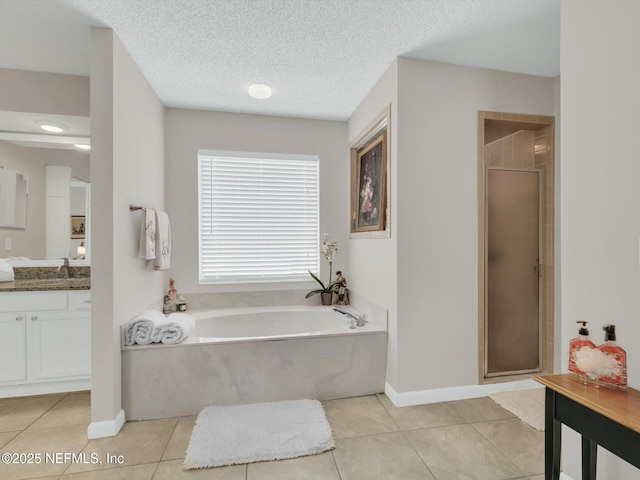 bathroom with a textured ceiling, tile patterned flooring, vanity, a bath, and a stall shower