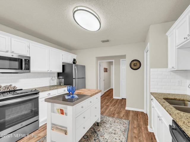 kitchen with white cabinetry, appliances with stainless steel finishes, light wood-style flooring, and a sink