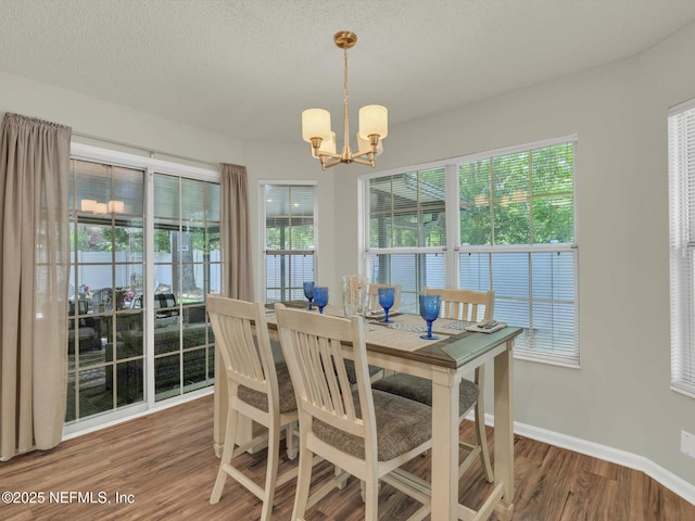 dining area with baseboards, a textured ceiling, an inviting chandelier, and wood finished floors