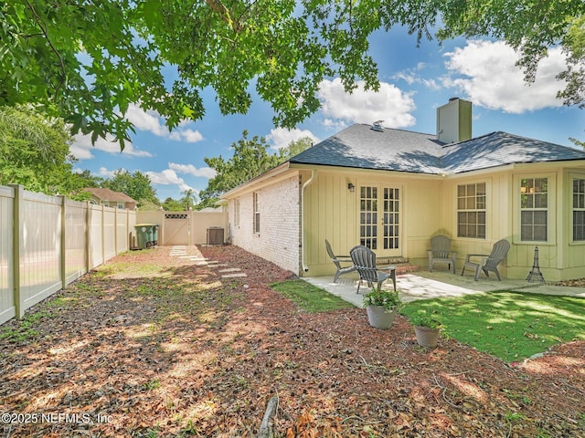 back of property featuring brick siding, a patio, a chimney, a gate, and a fenced backyard