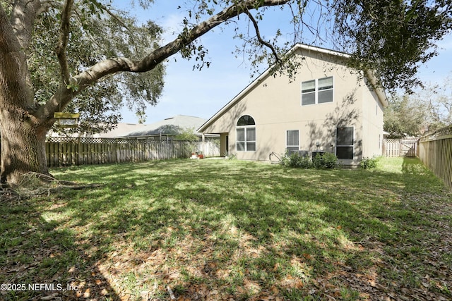 back of house with a lawn, a fenced backyard, and stucco siding