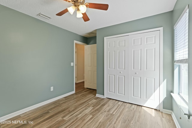 unfurnished bedroom with a closet, visible vents, baseboards, and wood finished floors