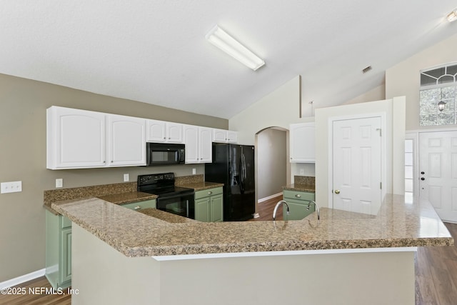 kitchen featuring visible vents, baseboards, vaulted ceiling, black appliances, and white cabinetry