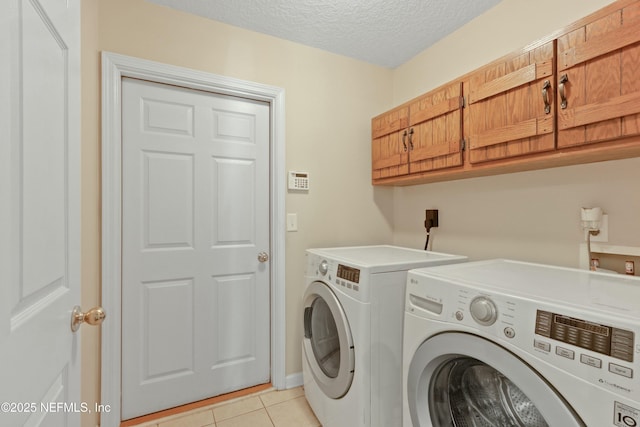 laundry area featuring light tile patterned floors, a textured ceiling, cabinet space, and washer and dryer