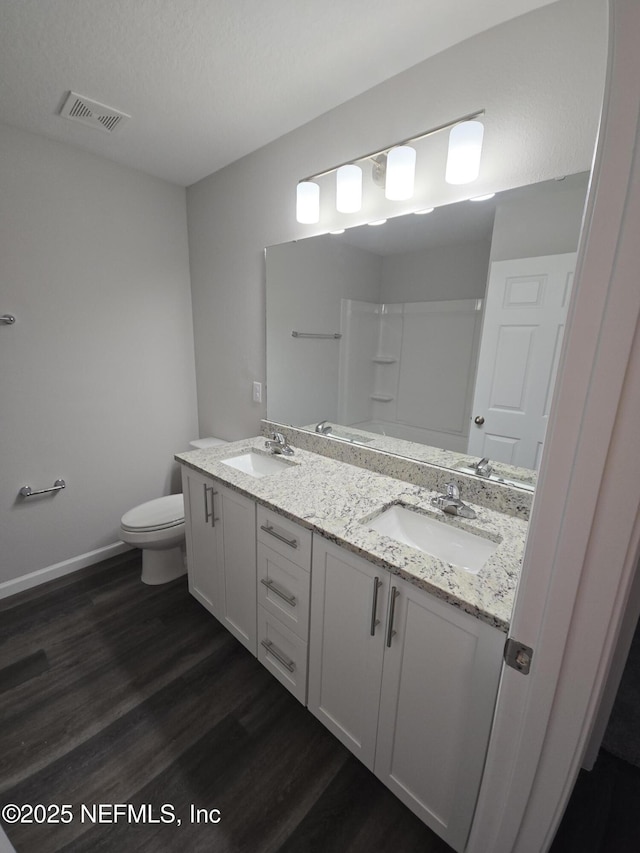 bathroom featuring visible vents, a sink, toilet, and wood finished floors