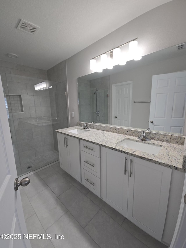 bathroom with double vanity, a sink, visible vents, and a shower stall