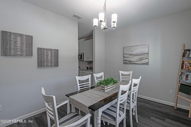 dining space with dark wood-style floors, baseboards, visible vents, and an inviting chandelier