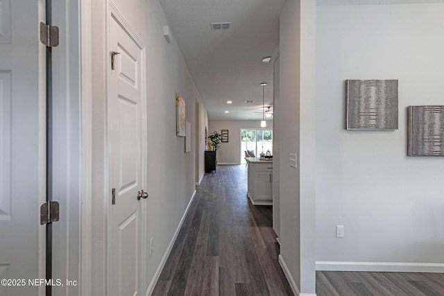 corridor with baseboards, visible vents, dark wood finished floors, and recessed lighting