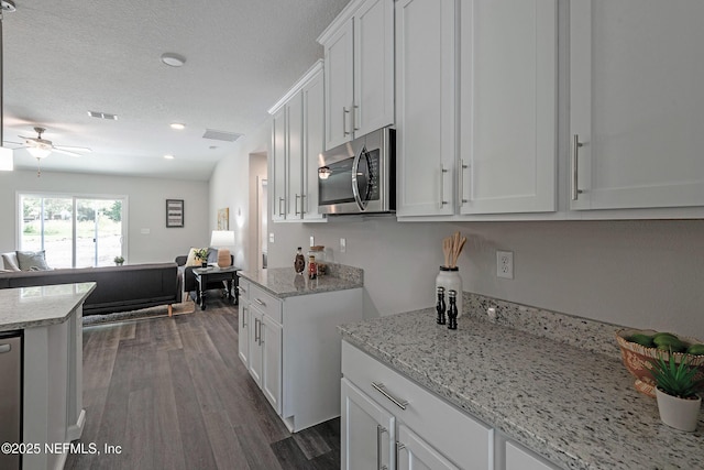 kitchen with stainless steel appliances, dark wood-style flooring, visible vents, white cabinets, and open floor plan