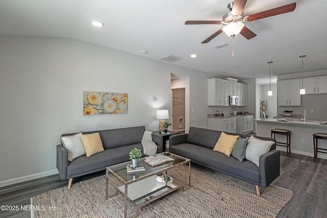 living room featuring ceiling fan, dark wood-type flooring, visible vents, and baseboards