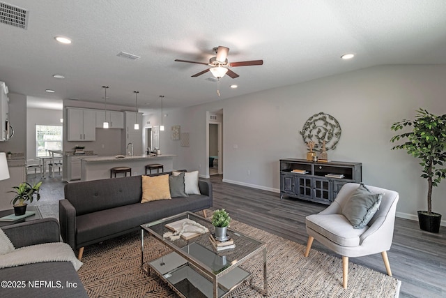 living room featuring baseboards, visible vents, a ceiling fan, wood finished floors, and a textured ceiling