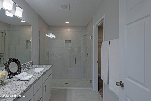 bathroom with a stall shower, visible vents, a spacious closet, a textured ceiling, and vanity