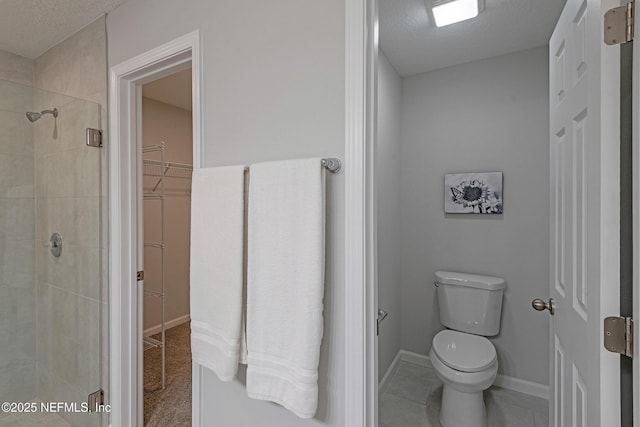 bathroom featuring a stall shower, a spacious closet, toilet, and a textured ceiling