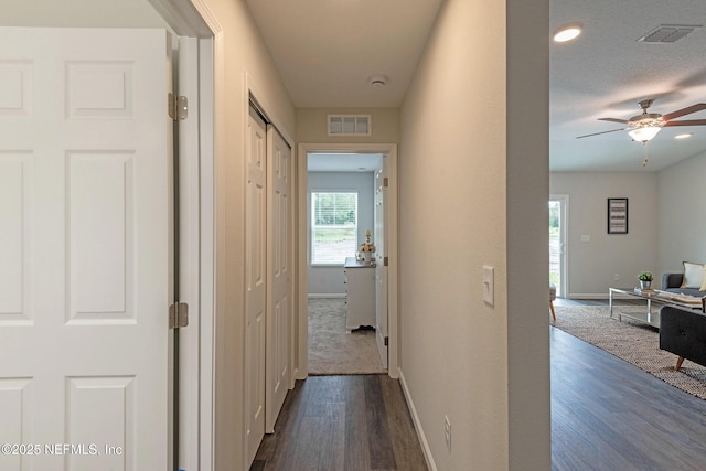 corridor featuring dark wood-style floors, visible vents, and baseboards