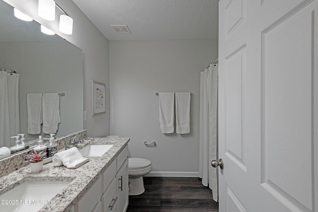 full bathroom featuring a textured ceiling, visible vents, a sink, and wood finished floors