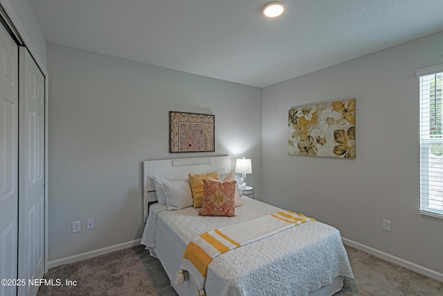 bedroom featuring a closet, carpet flooring, a textured ceiling, and baseboards