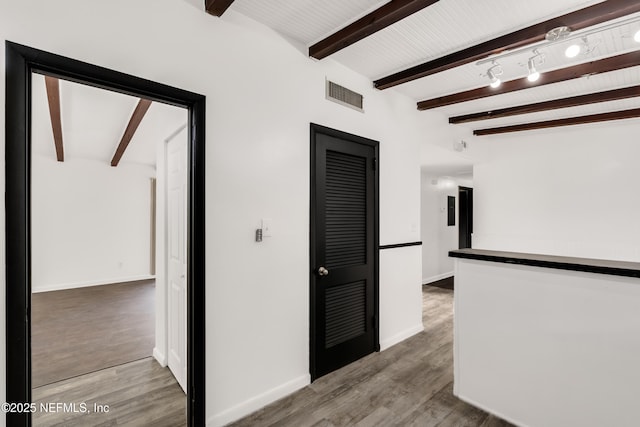 hallway featuring visible vents, beamed ceiling, baseboards, and wood finished floors