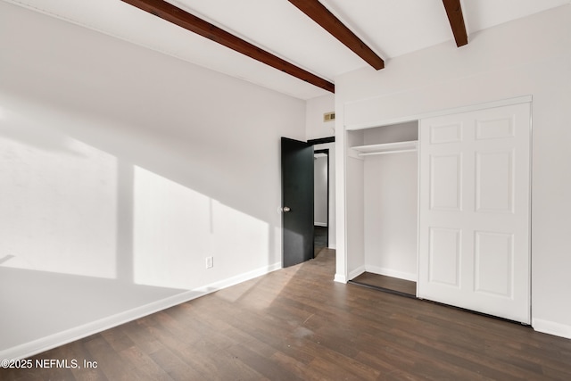 unfurnished bedroom with dark wood-style floors, a closet, beamed ceiling, and baseboards