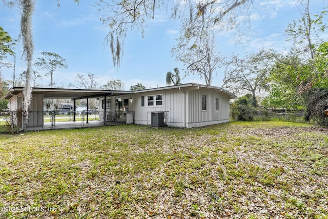 rear view of property featuring an attached carport, central air condition unit, fence, a yard, and a gate