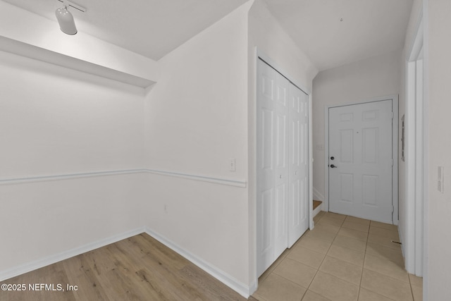 hall featuring light tile patterned floors and baseboards