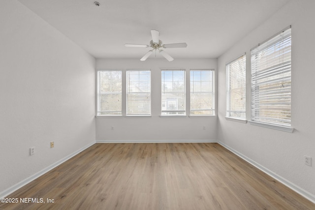 spare room with light wood-style floors, a healthy amount of sunlight, ceiling fan, and baseboards