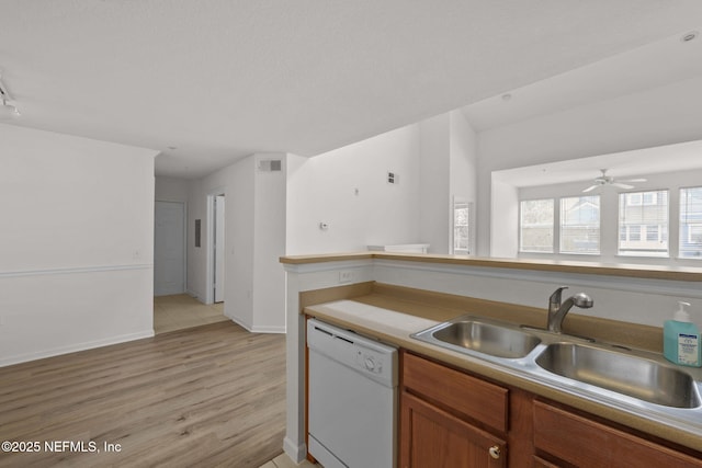 kitchen with a sink, visible vents, light wood-type flooring, dishwasher, and brown cabinetry