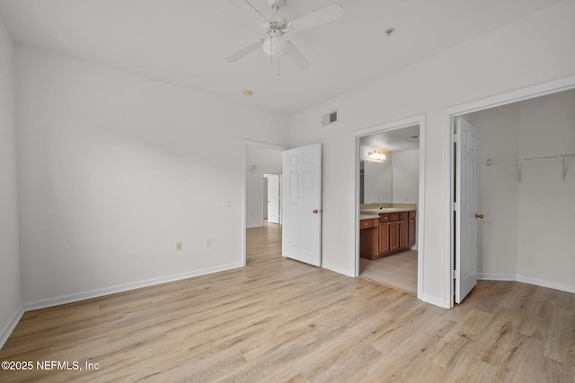 unfurnished bedroom with light wood finished floors, visible vents, ensuite bathroom, a sink, and baseboards